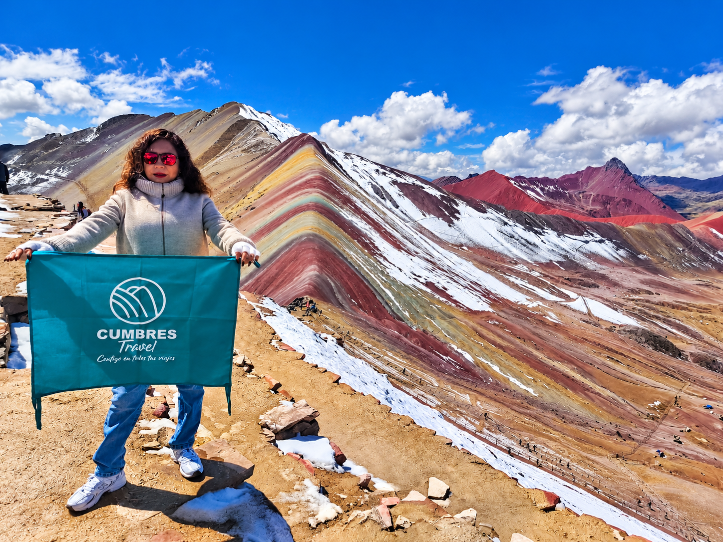 Viajera con bandera de Cumbres Travel en la Montaña Arcoíris